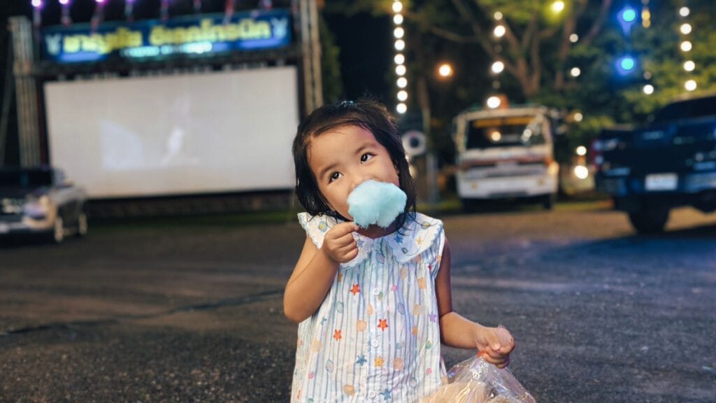 เด็กหญิงถือขนมสายไหมและข้าวเกรียบว่าว