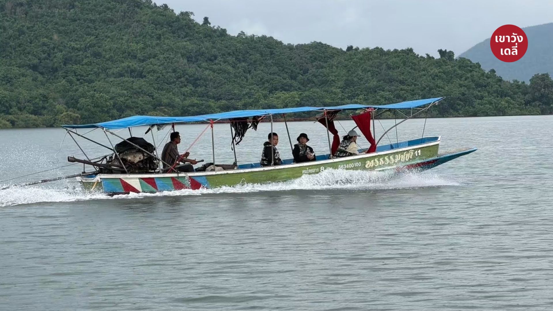 เรือหางยาวนำเที่ยวแล่นผ่านผืนน้ำในอ่างเก็บน้ำแก่งกระจาน มุ่งหน้าสู่จุดสตาร์ตบ้านพุเข็ม พร้อมโลโก้เขาวังเดลี่