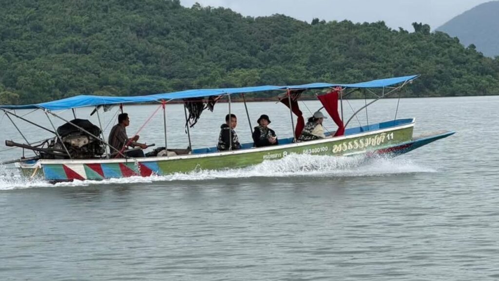 เรือหางยาวนำเที่ยวแล่นผ่านผืนน้ำในอ่างเก็บน้ำแก่งกระจาน โดยมีผู้โดยสารนั่งอยู่บนเรือ